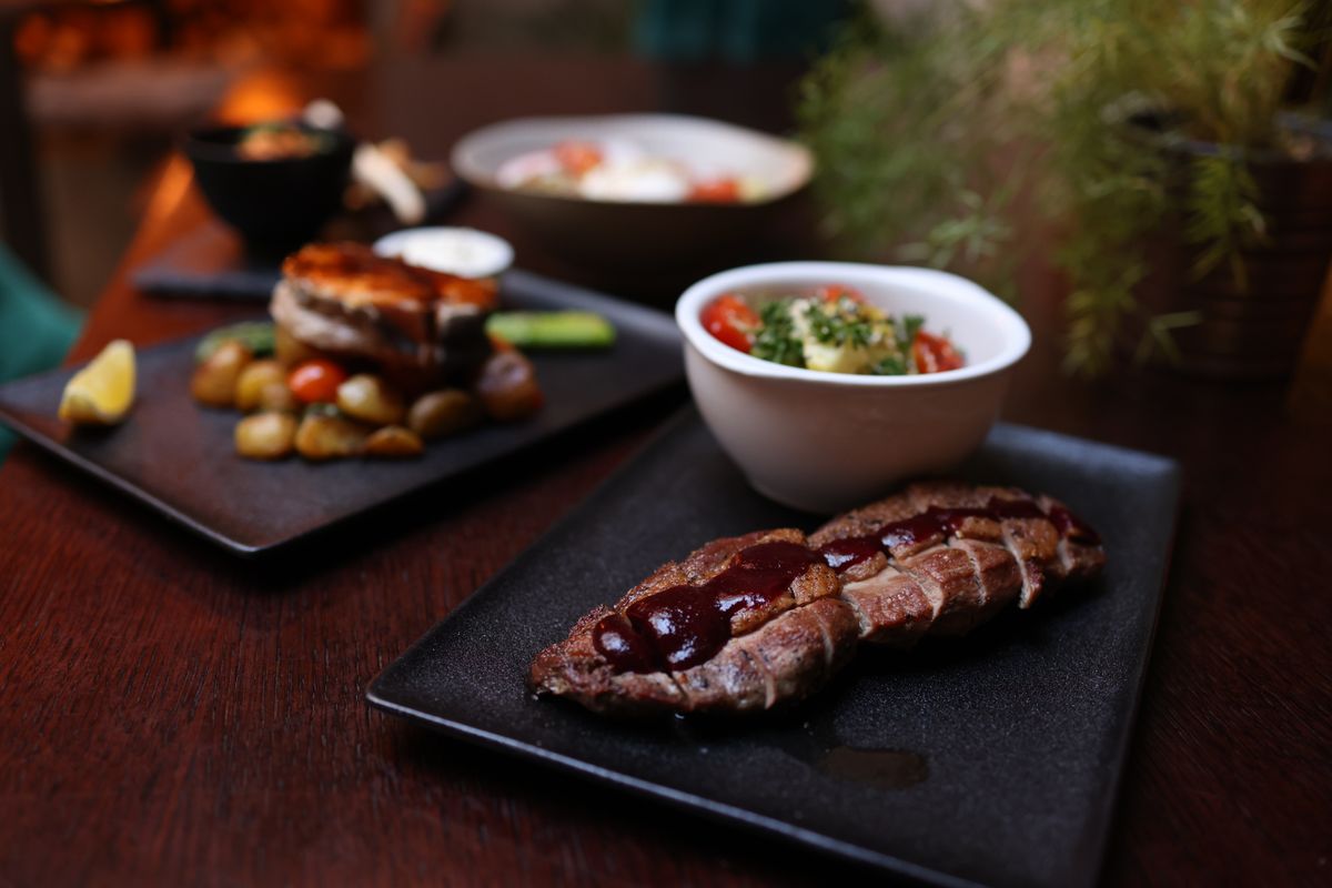Cast-iron seared bone-in ribeye with roasted sides on a dark plate