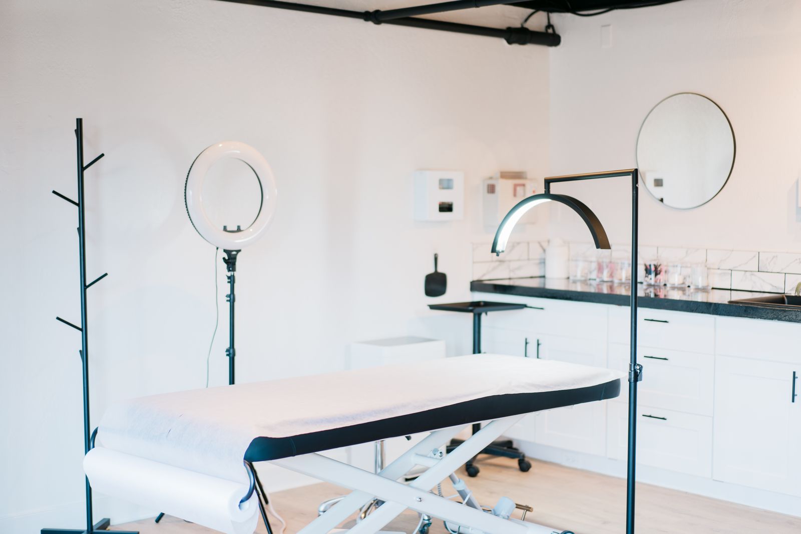 A bright treatment suite with soft daylight, a ring light, and a prepared treatment bed