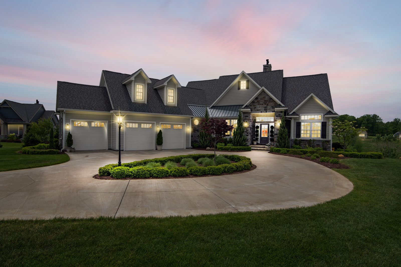 Larkspur House — a brick custom home with a gabled roofline and warmly lit windows at dusk
